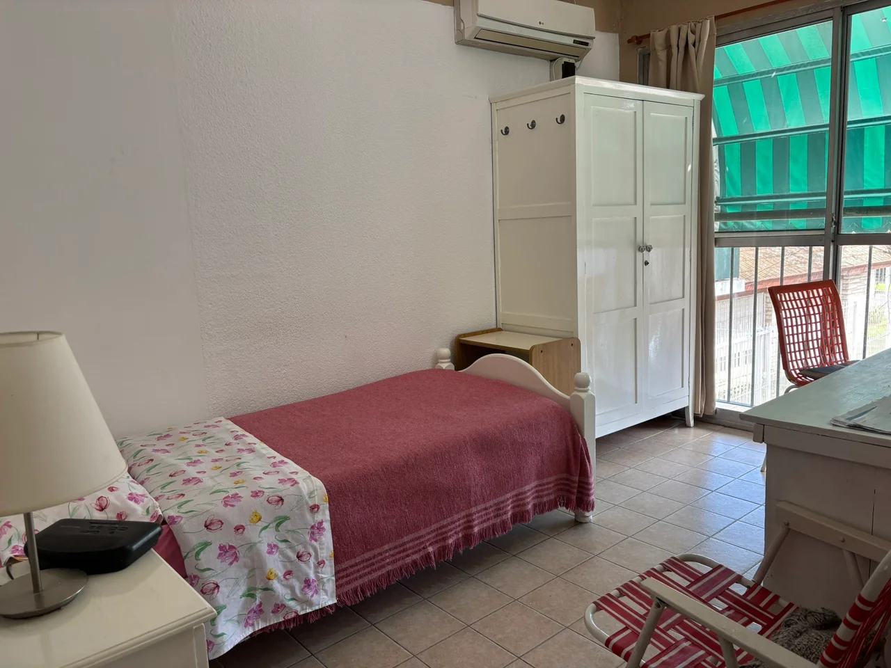 Habitación con cama de cubrecama bordó, placard blanco y ventana amplia.